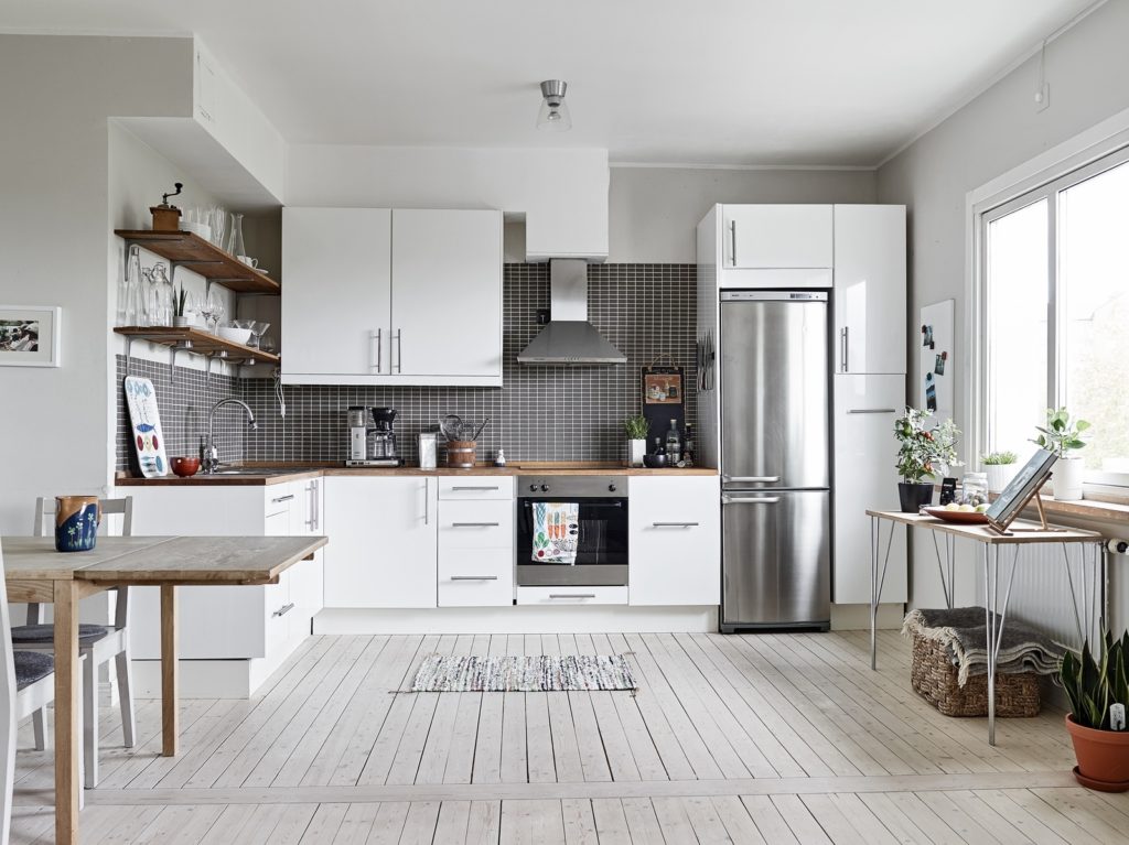 Холодильник серебристого цвета в интерьере белой кухни 