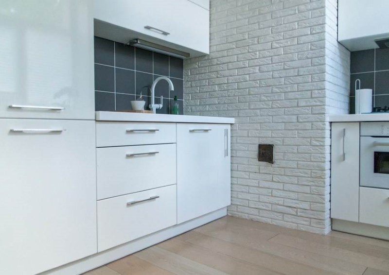 Белый интерьер кухни в стиле минимализма с кирпичной стеной