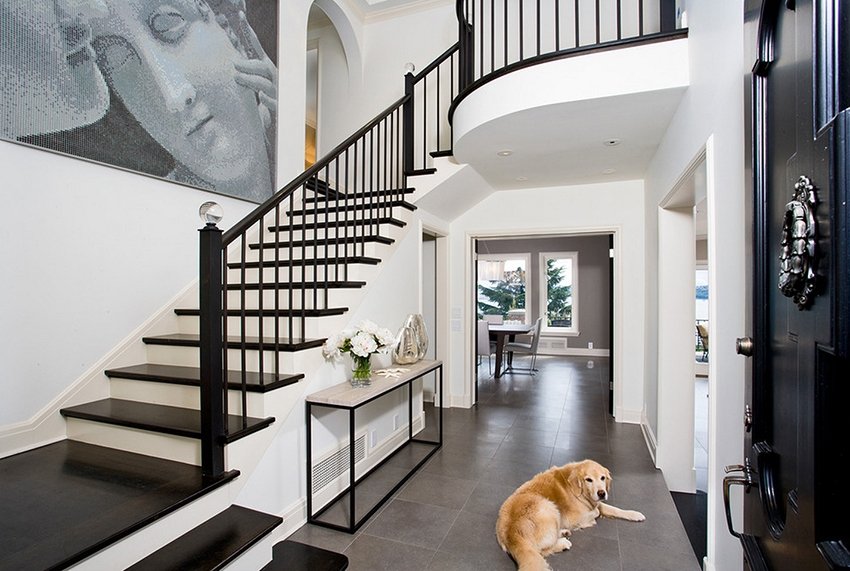 Большая собака на полу прихожей с лестницей