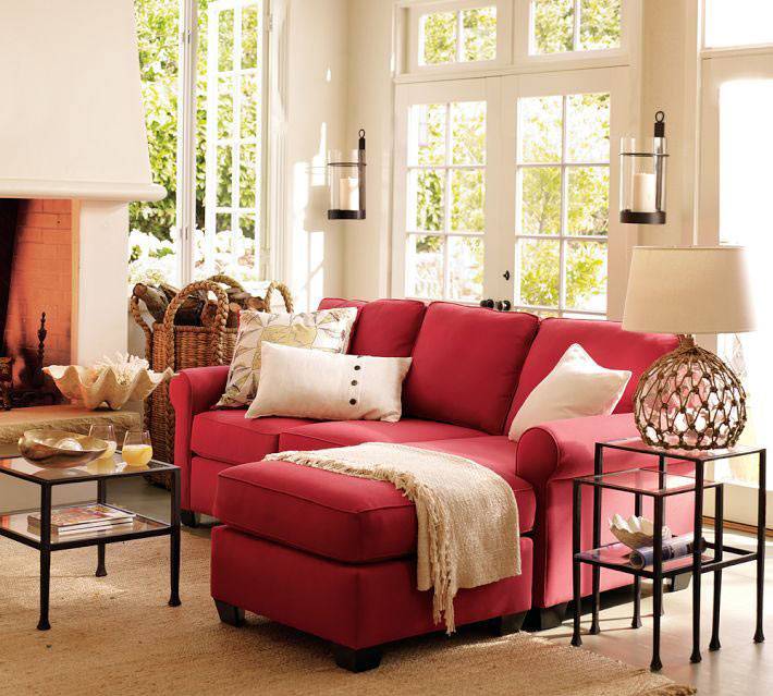 ярко красный угловой диван с белыми подушками в интерьере комнаты