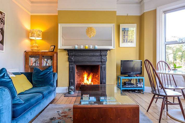 яркий интерьер гостиной: желтые стены и синий диван