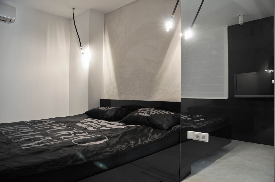 Черная кровать на фоне белой стены в спальне