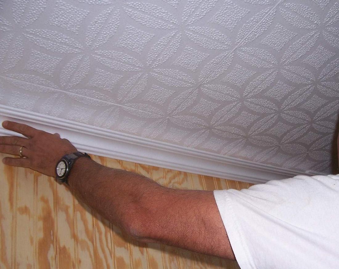 После нанесения клея на плинтус его необходимо плотно прижать к поверхности потолка и стены обеими руками 