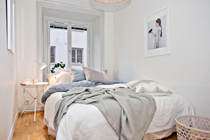 Белая двухспальная кровать в интерьере узкой спальной комнаты