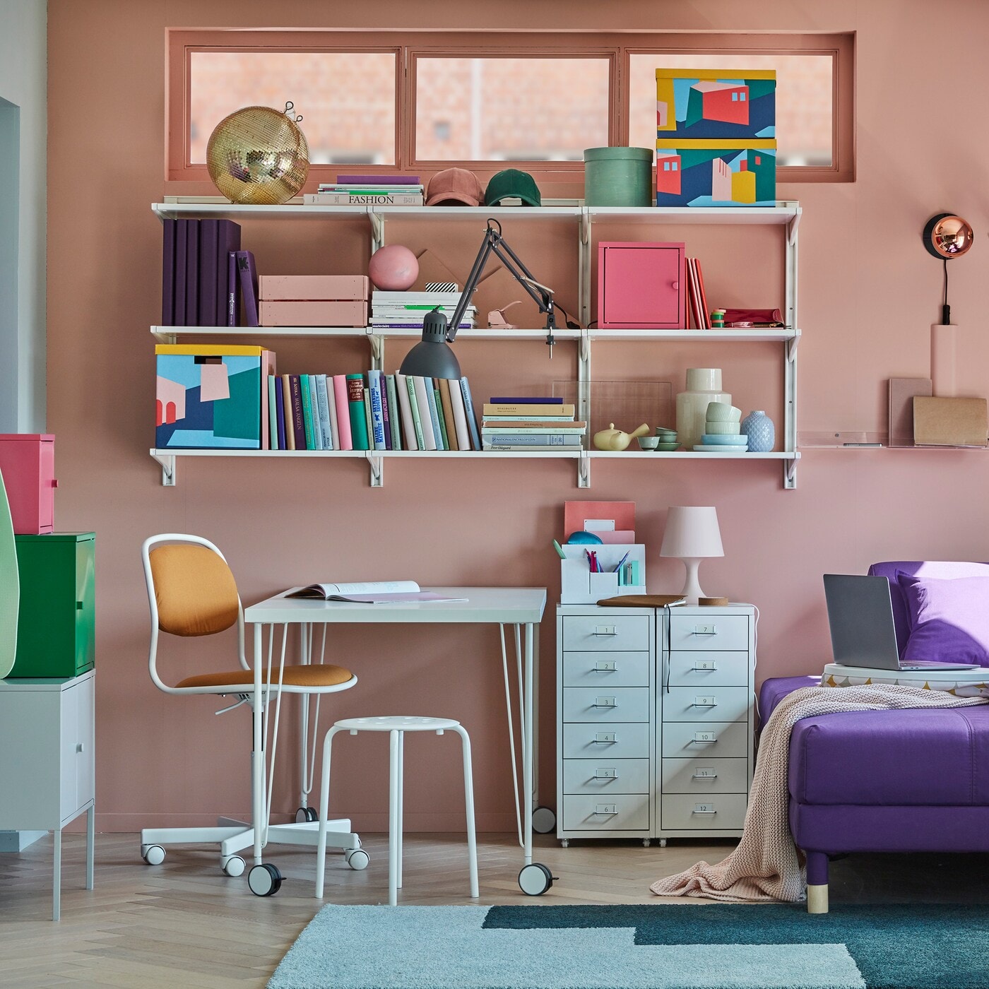 Small home office, with a LINNMON/KRILLE table in white with legs on castors, some shelves, storage cabinets and a sofa bed.